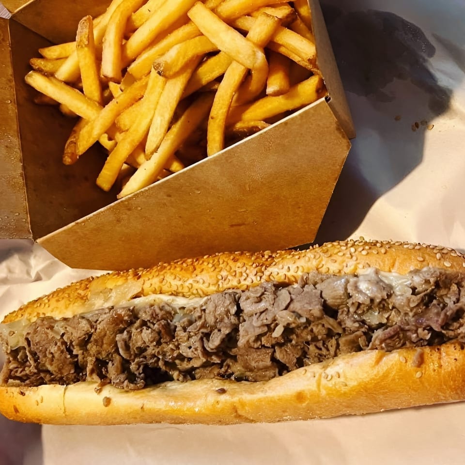 Brynn Bradley's cheesesteak sandwich with melted cheese and a side of golden french fries.